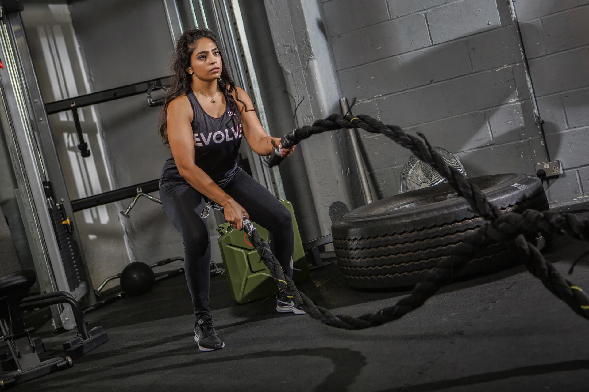 Evolve member training with battle ropes on the gym floor